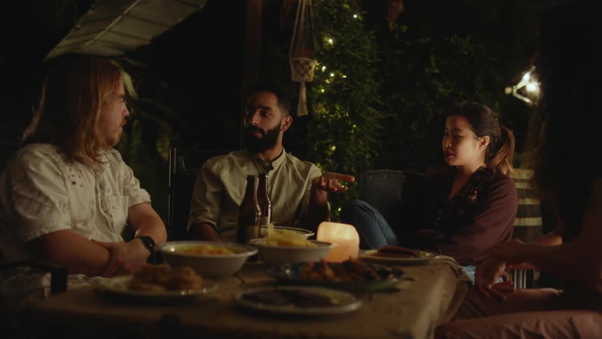 Group of friends relaxedly chatting around the dinner table at home