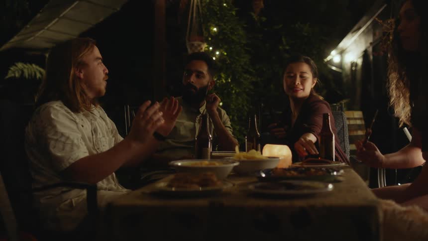 A group of friends are eating at a restaurant during the night time