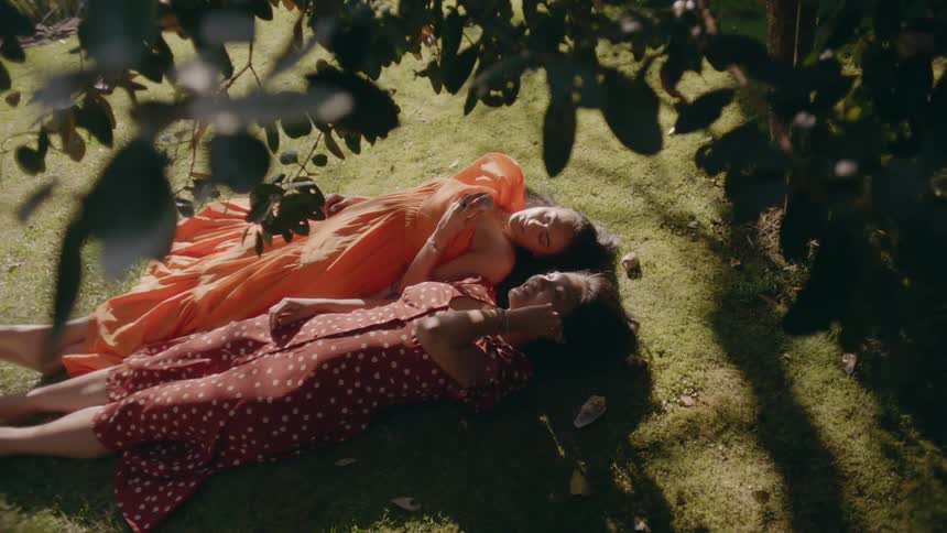 Two women lay together in the grass