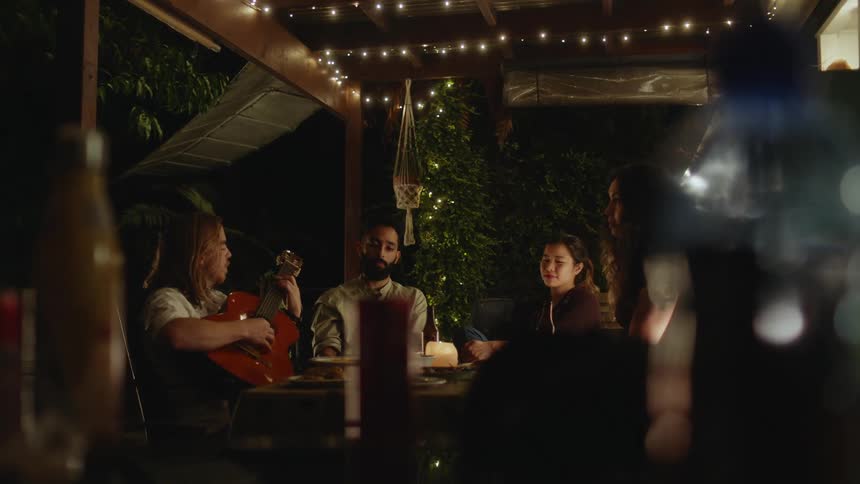 Friends listen to a man play the guitar