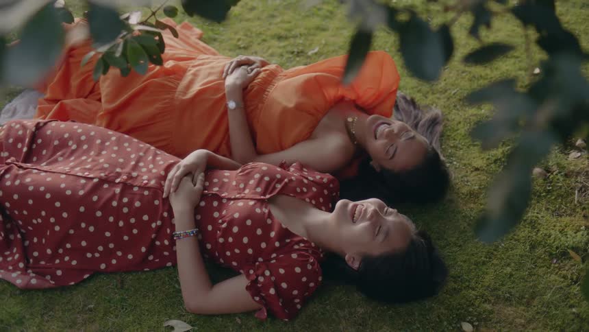 Two women are laying on a grass field during spring