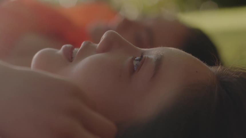 A close up of a womans face as she smiles looking upwards as she lay on her back