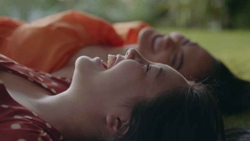 Two ladies are lying on the ground enjoying a fun conversation and laughing together