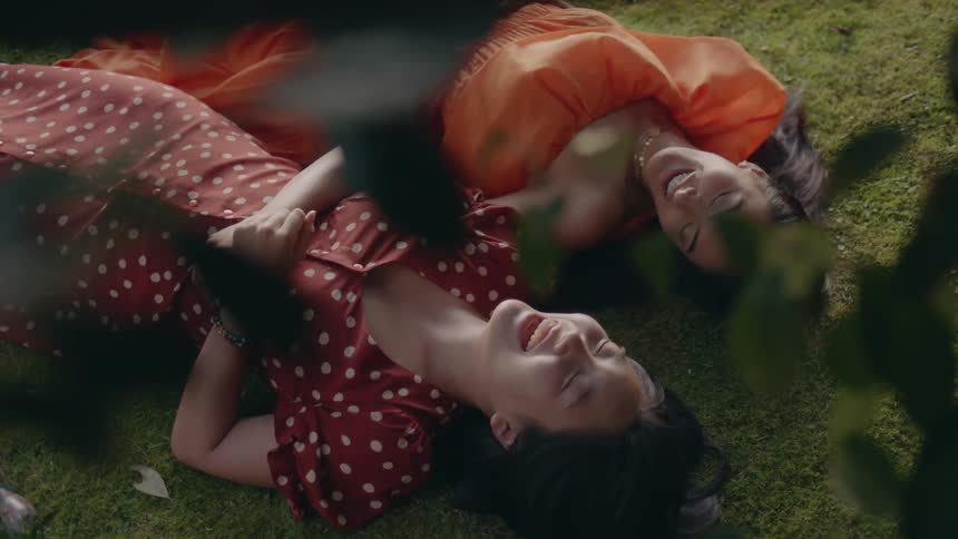 Two women laying on the ground laughing together and looking at each other