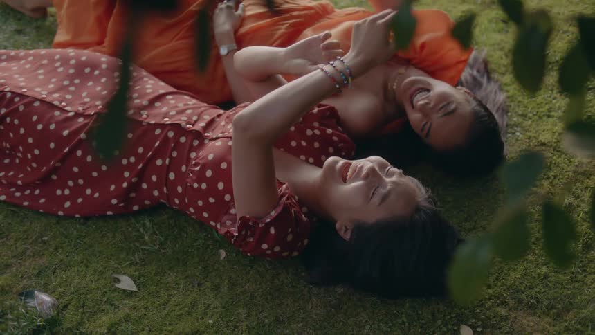 Two women are laughing and laying outdoors during spring