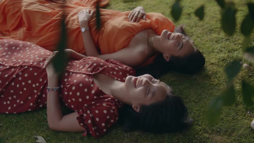 Two girls are laying in a grass field together
