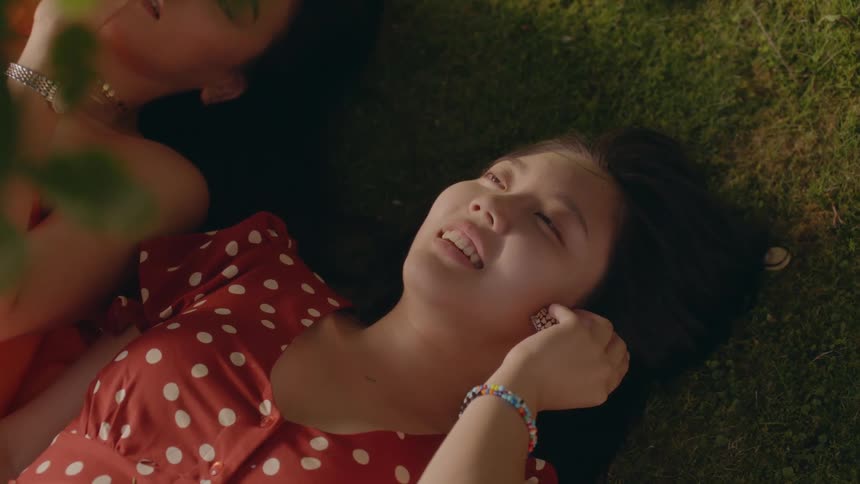 Two female friends are laying in the grass together