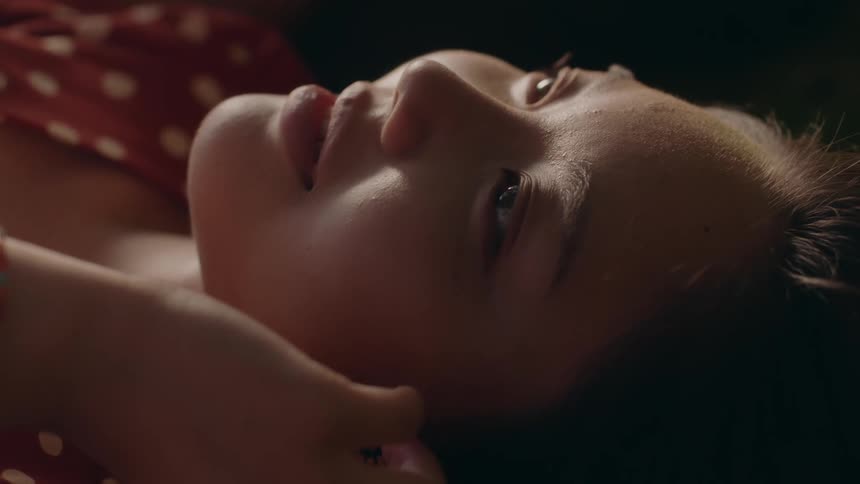 A close up of a womans face and hand as she looks upwards