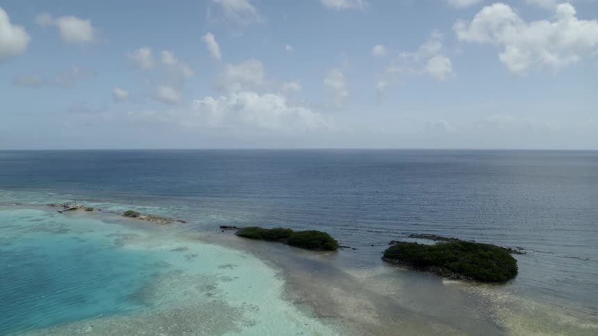 Pullback reveal of small islands and reefs dotted along stunning blue and turquoise water