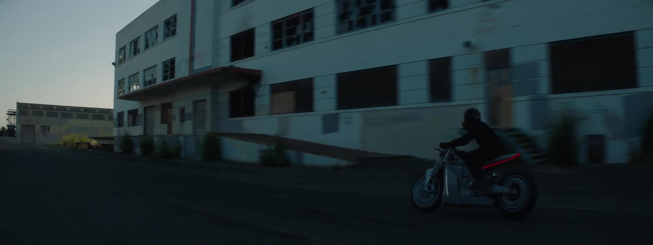 A person rides his motorcycle past the building