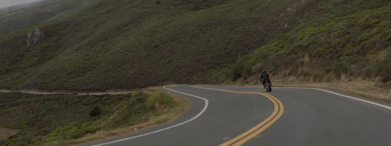 A person rides a motorcycle along a curvy mountain road