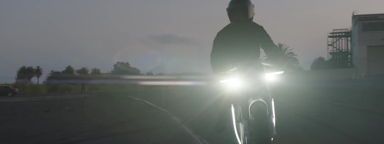 Person on motorcycle riding along pacific coast highway at sundown
