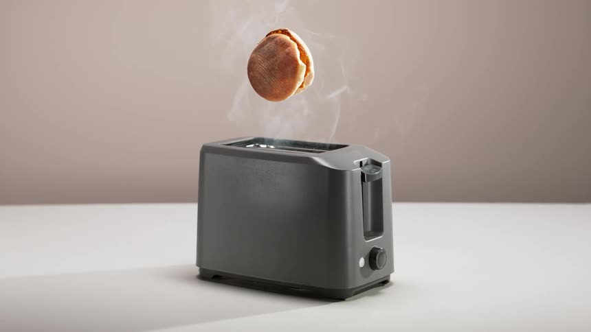 Slices of bun spring into the air from smoking toaster