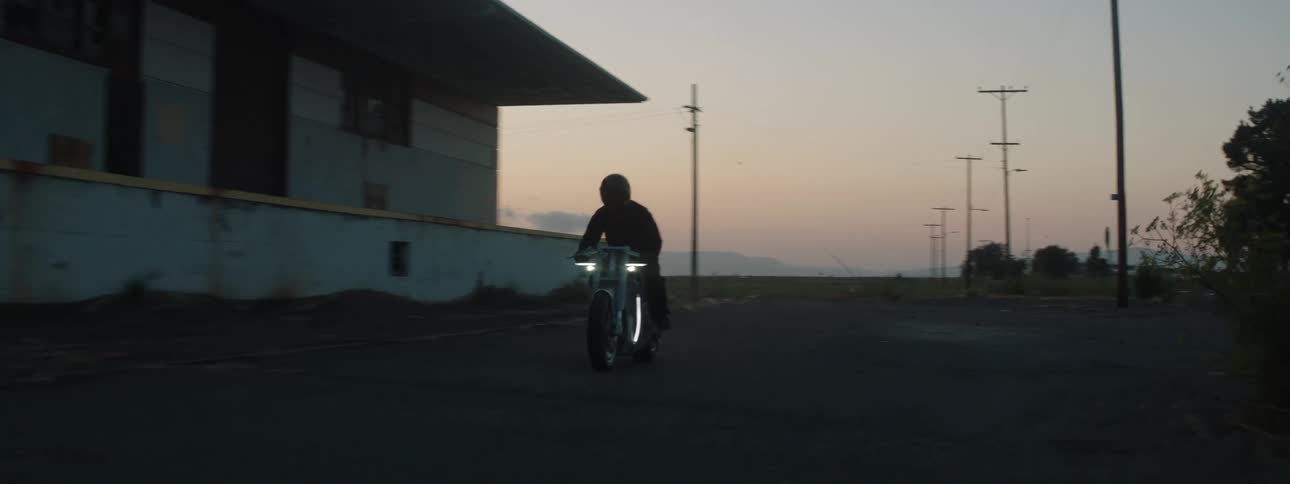 A man rides his motorcycle through a rural town