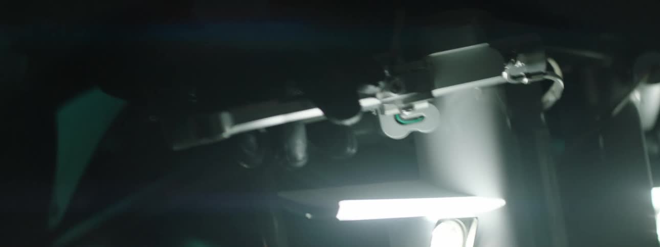 A gloved hand is grasping the handle bar of a fast moving bike on a bumpy terrain with a bright white light in the front illuminating the dark around it