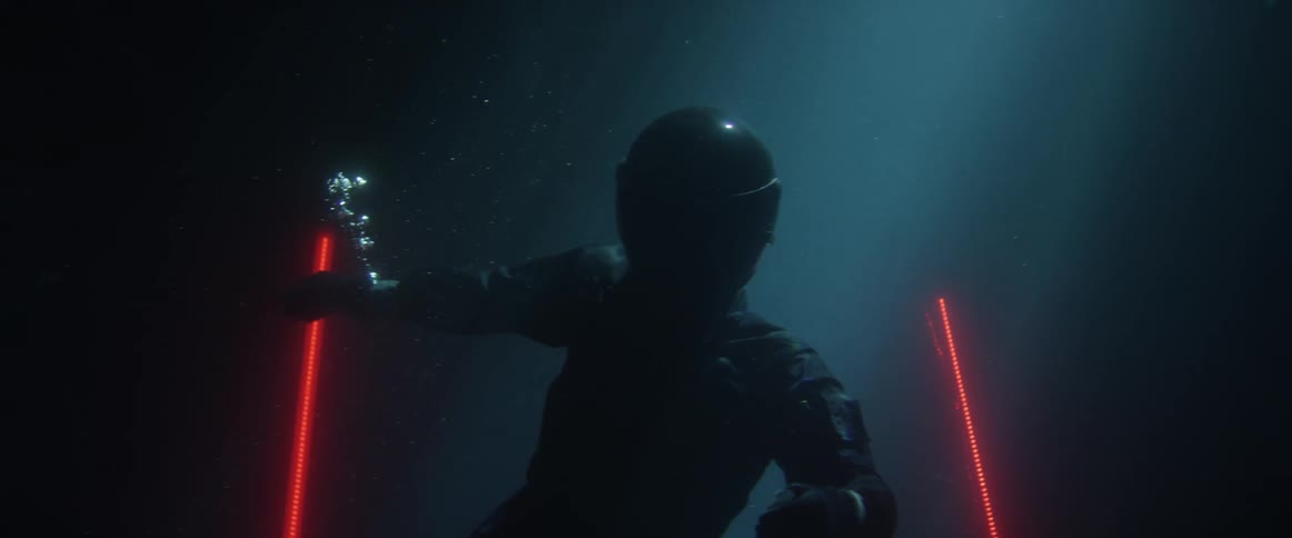 A person in a black suit and helmet floatingin water and then swimming