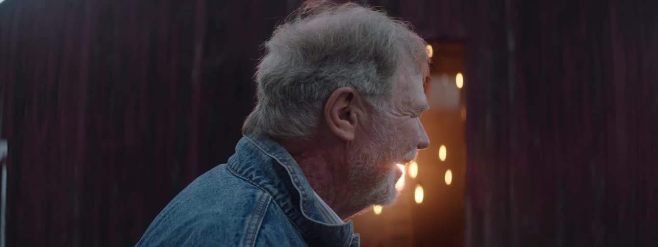 An old man with a happy expression on his face smiling and nodding his head