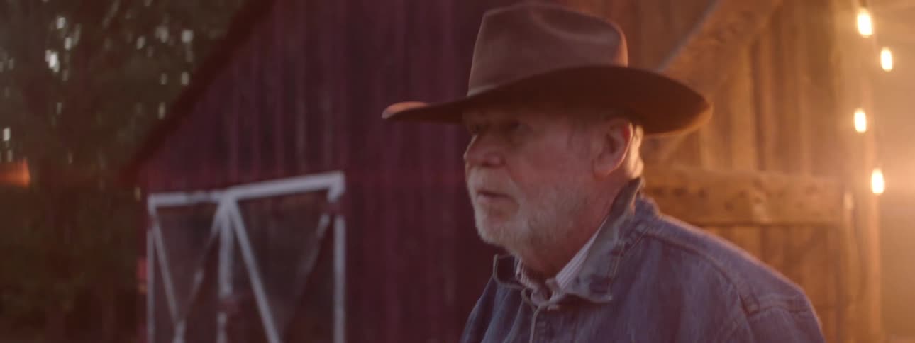 An elderly man wearing a hat walking out of a door in an angry manner