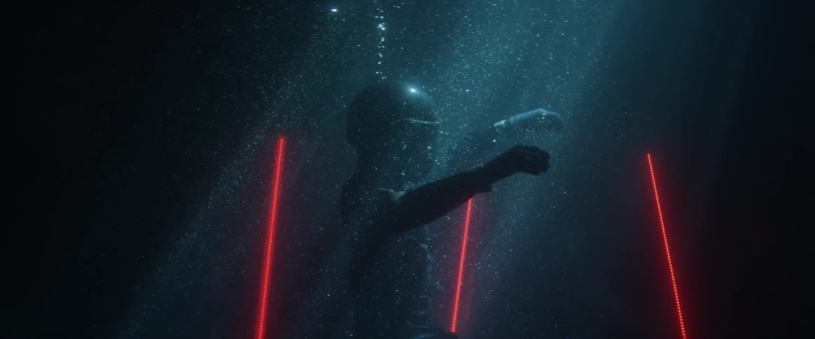 Surreal footage of a motorcycle driver wearing a crash helmet floats underwater surrounded by red lights