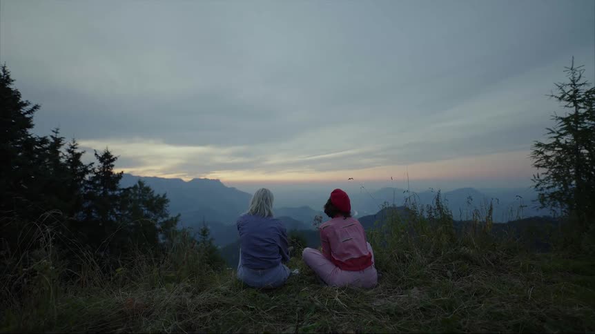 Two people sit on the mountain together