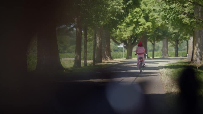 Woman wearing red beret pink shirt and pants rides bicycles on country road