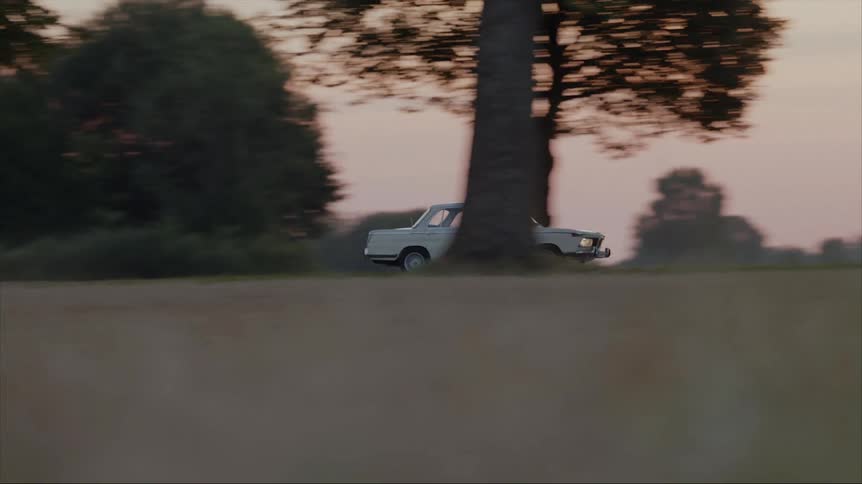 A car is driving through a rural area at dusk