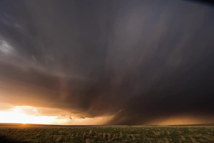 Lighning strikes through dense clouds over a field