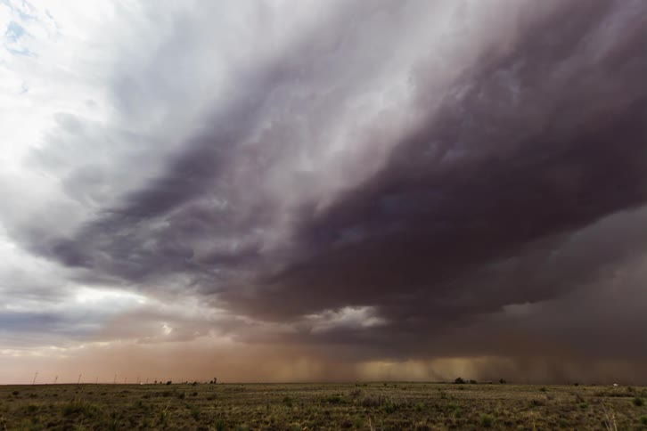 Dark ominous storm clouds move over rural land pouring rain on the ground as it moves