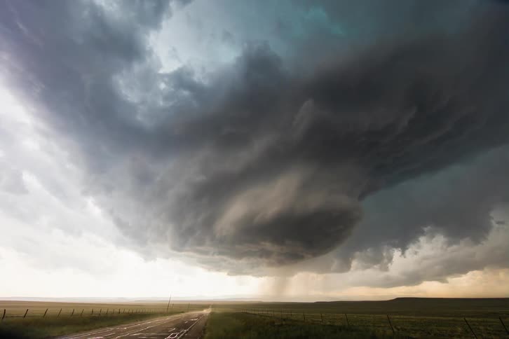 Cars move along country road as storm clouds start rotating