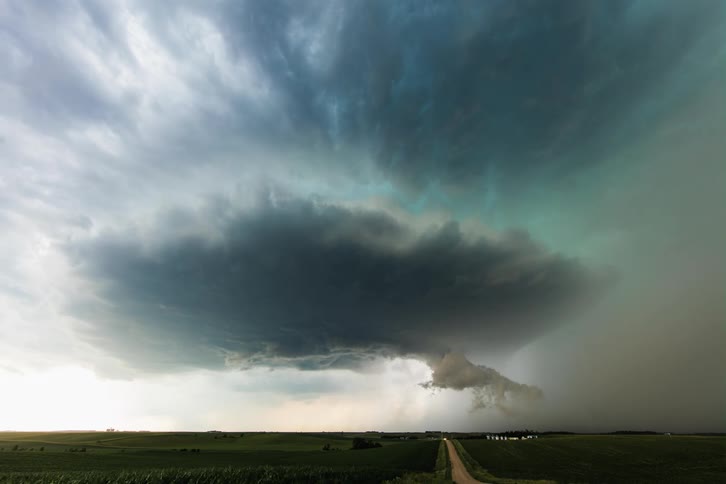 Vehicles move along dirt road throughcountryside as storm clouds rotate
