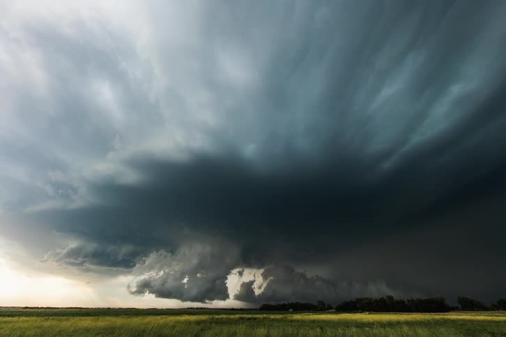 A gigantic storm cloud is forming in the sky in a vortexlike formation