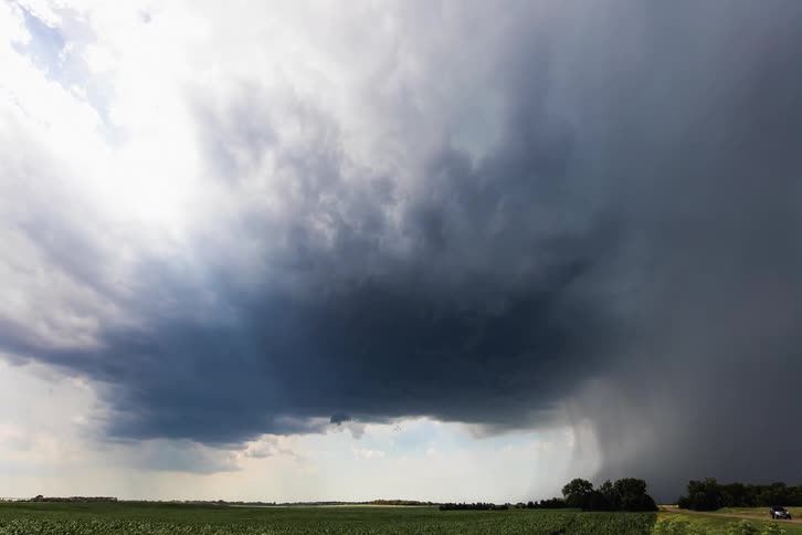 Landscape of dark storm clouds floating in the sky over green field