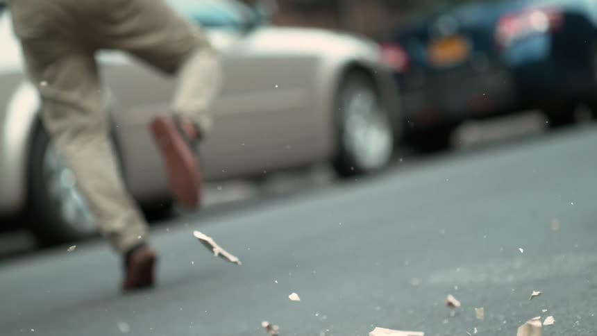 A man avoids a falling vase that smashes onto the pavement