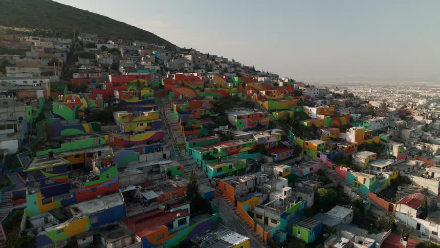 Multicolored houses sit on slope overlooking valley and town