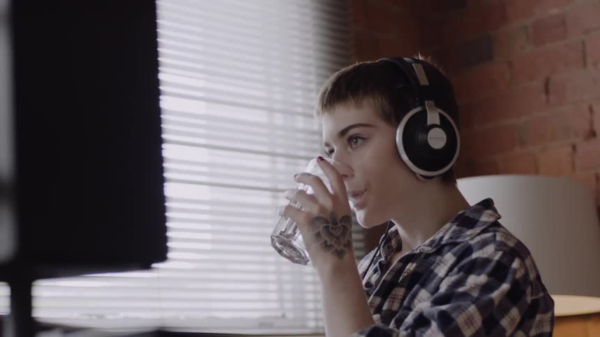 Woman wearing headphones takes a sip of water