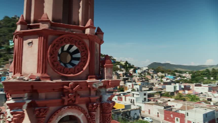 A colorful tower sits over a neighborhood near mountains