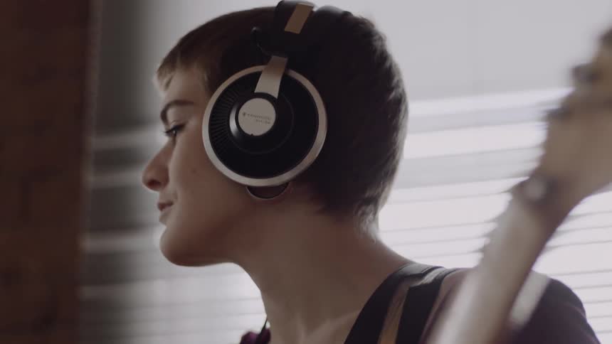 Woman wearing headphones plays the guitar