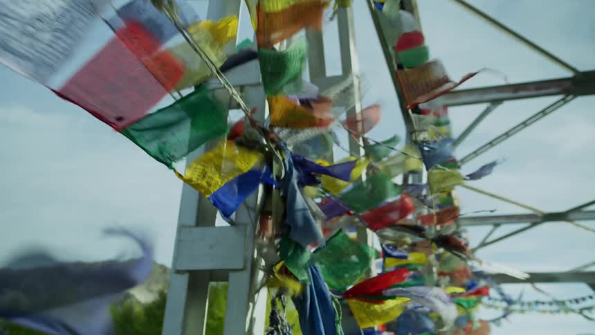 Banners with small flags are attached to a bridge near a mountain range