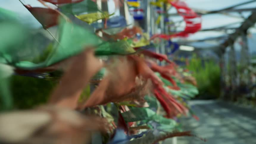 Colorful flags are tied to a bridge while blowing in the wind on a sunny day