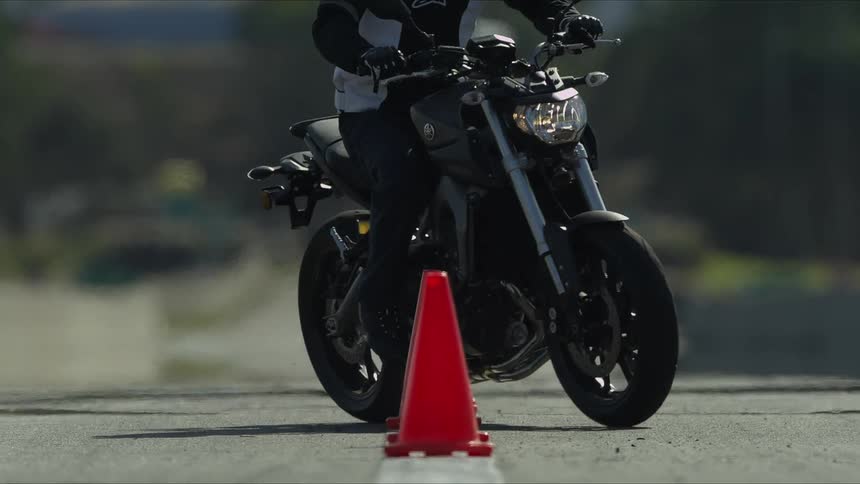 A person skillfully steers a motorcycle through a line of orange cones