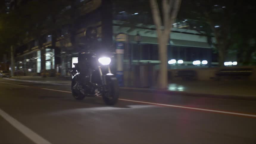 A person is driving a motorcycle through a city at night