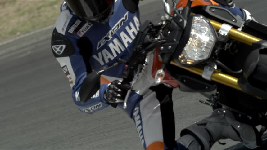 A motorcycle racer travels around a bend holding the handlebars of his motorcycle and he leans around the banked curve