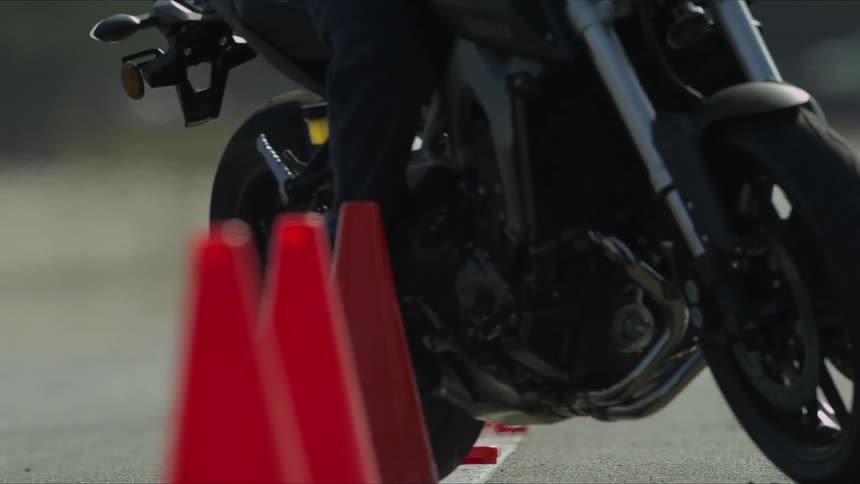 A motorcyclist is ridden and weaving back and forth through orange traffic cones