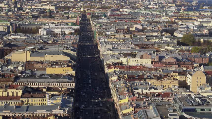 An aerial of a dense city with buildings touching each other and traffic driving on the streets
