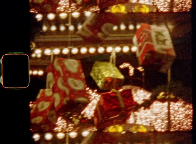 Handheld old Super-8 film footage of glowing shining lights and wrapped Christmas gifts that are hanging and dangling in a market stall on a X-mas fair with magical atmosphere on Christmas Eve or Boxing Day celebrating kindness giving and togetherness