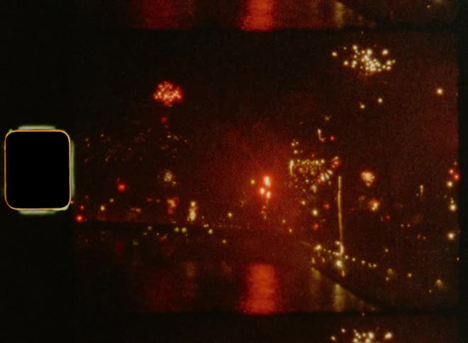 Vintage footage of colourful fireworks show reflecting on the surface of a body of water