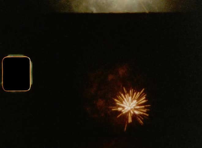 Vintage footage of bright sparkles of colorful fireworks exploding in the dark night sky