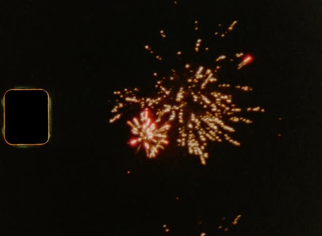 Fireworks explode in starburst patterns in the night sky on old analogue film