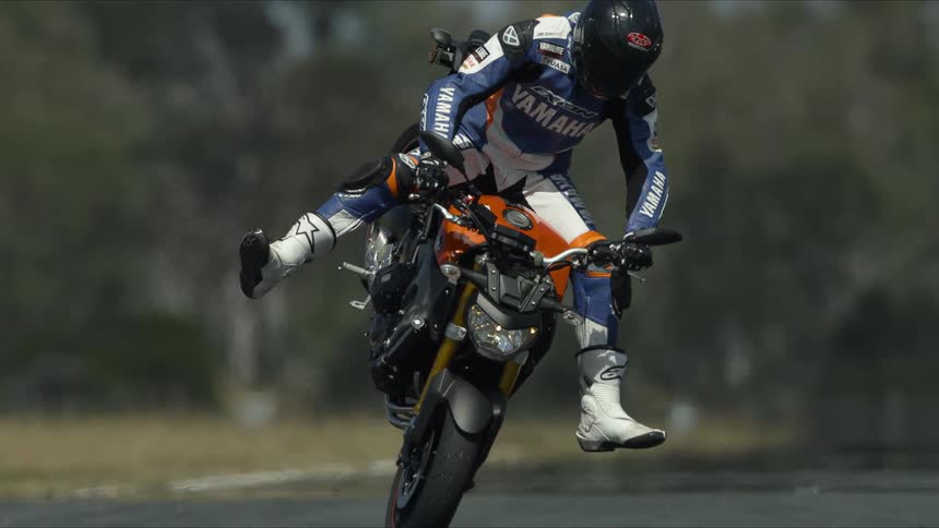 A man is riding a motorcycle and doing tricks