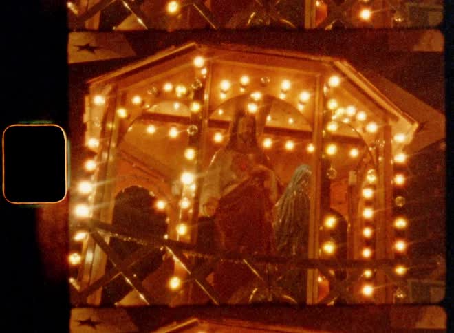 A wooden statue of a man that bears a resemblance to Jesus Christ is enclosed in a lit and rotating Christmas pyramid creating a holy mesmerizing effect with a holiday spirit and a festive atmosphere as Christian symbol and traditional celebration